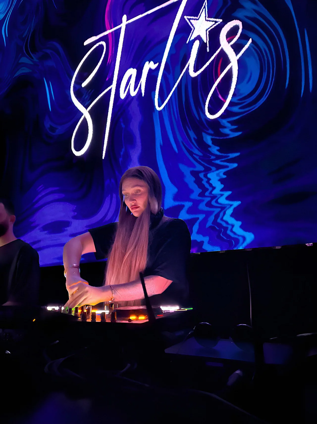 Zanna, vocalist, performing live under her glowing neon logo during a peak-time club show